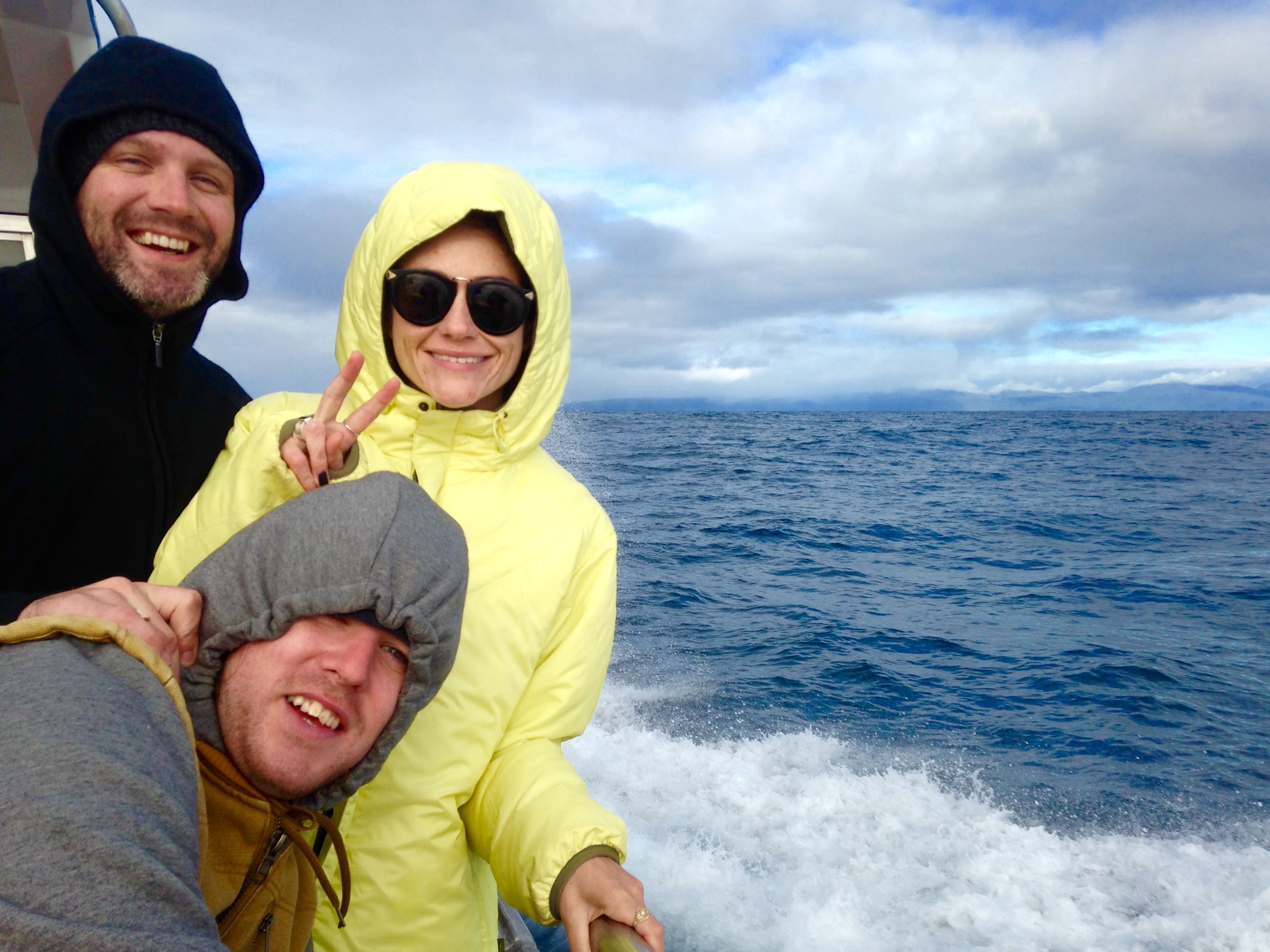 Three guests enjoy the wind on the Stewart Island, with their hoods up