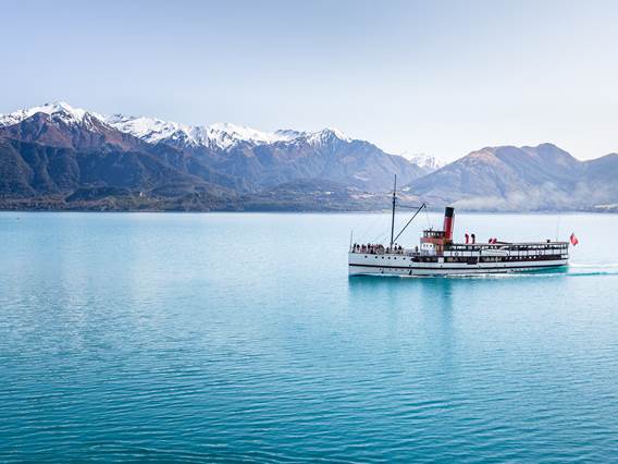 The historic TSS Earnslaw Steamship cruises along Lake Wakatipu with a view of The Remarkables mountain range 