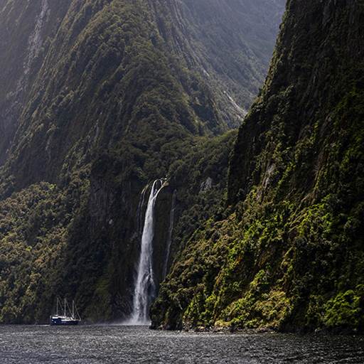 The Milford Mariner vessel cruises close to a cascading waterfall in Milford Sound