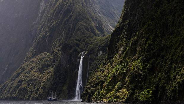 The Milford Mariner vessel cruises close to a cascading waterfall in Milford Sound