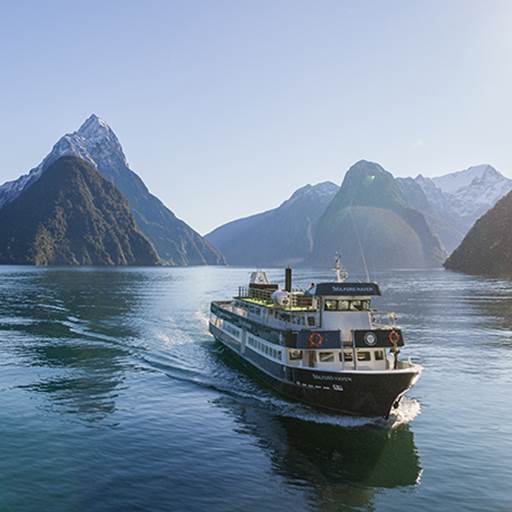 The Milford Haven vessel cruises through Milford Sound on a clear day, with a snowy Mitre Peak in the background 