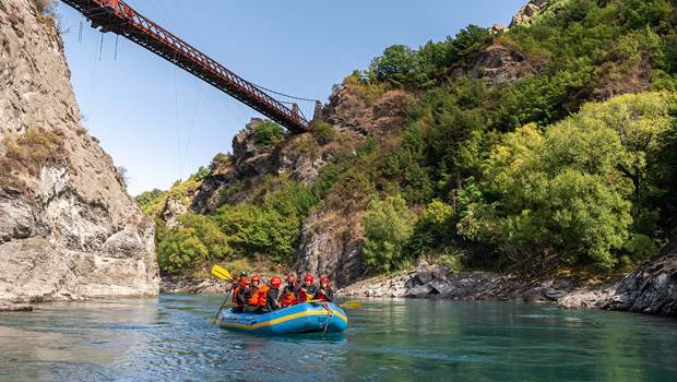 A rafting group float under the Kawarau bridge on a cleat blue day 
